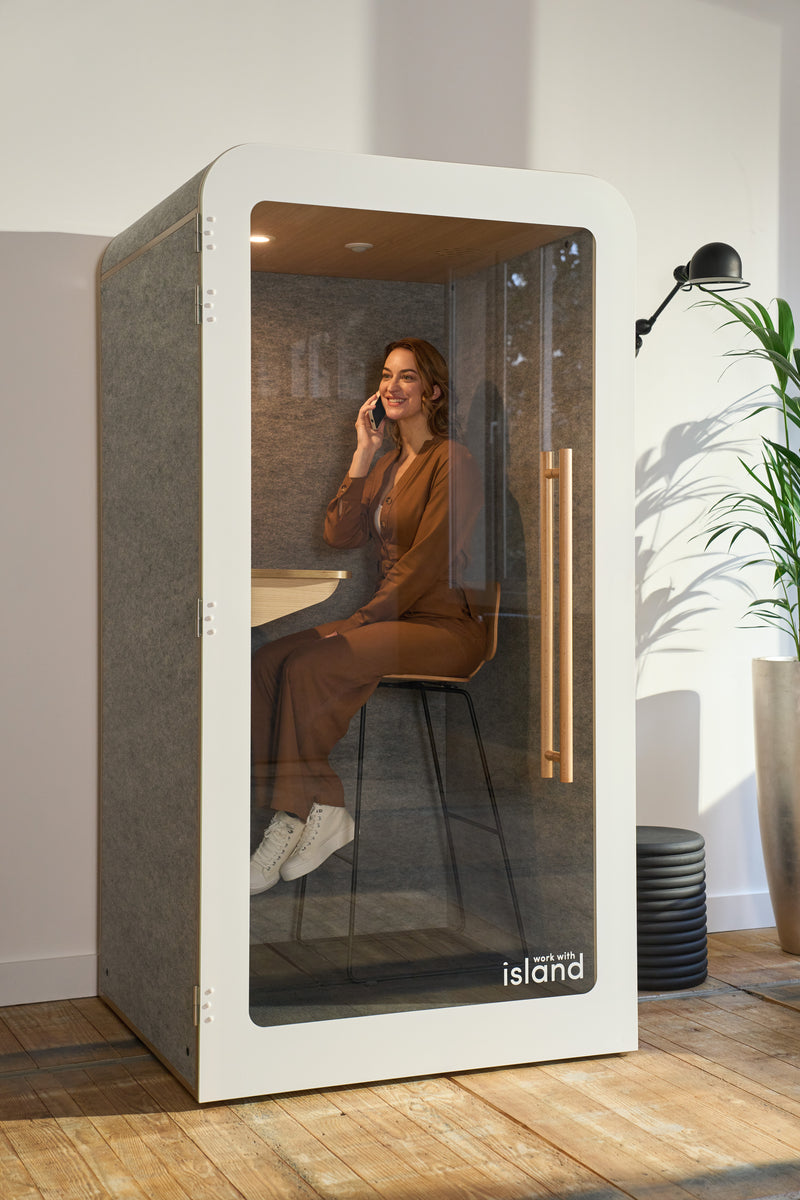 espace de bureau aménagé avec une cabine insonorisée individuelle et une femme au téléphone qui travaille.