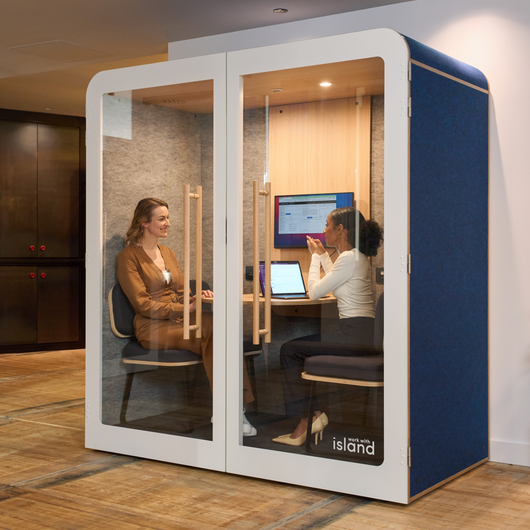 Open space aménagé avec une cabine acoustique 2 personnes où deux femmes travaillent