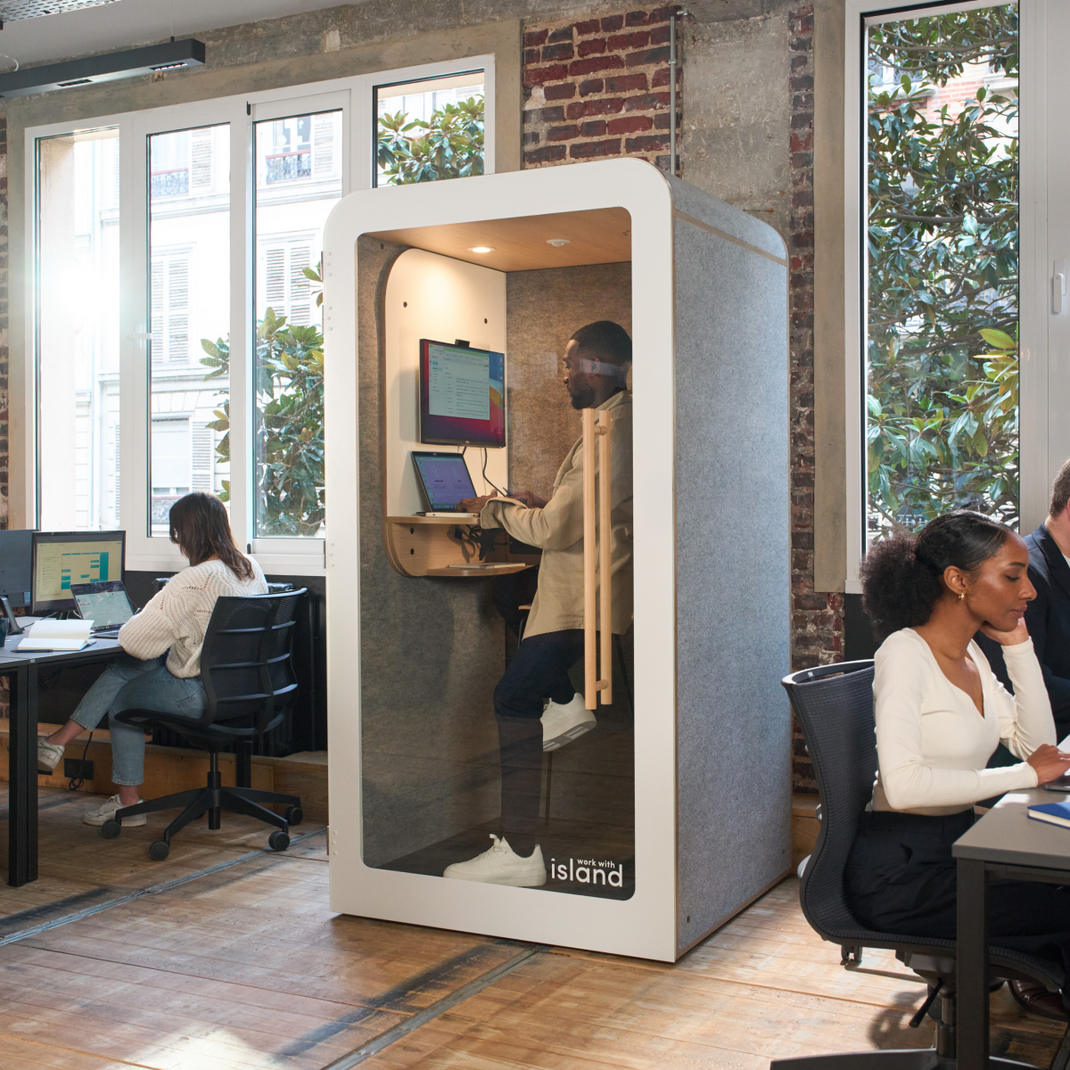 Open space aménagé avec une cabine insonorisée individuelle où un homme travaille
