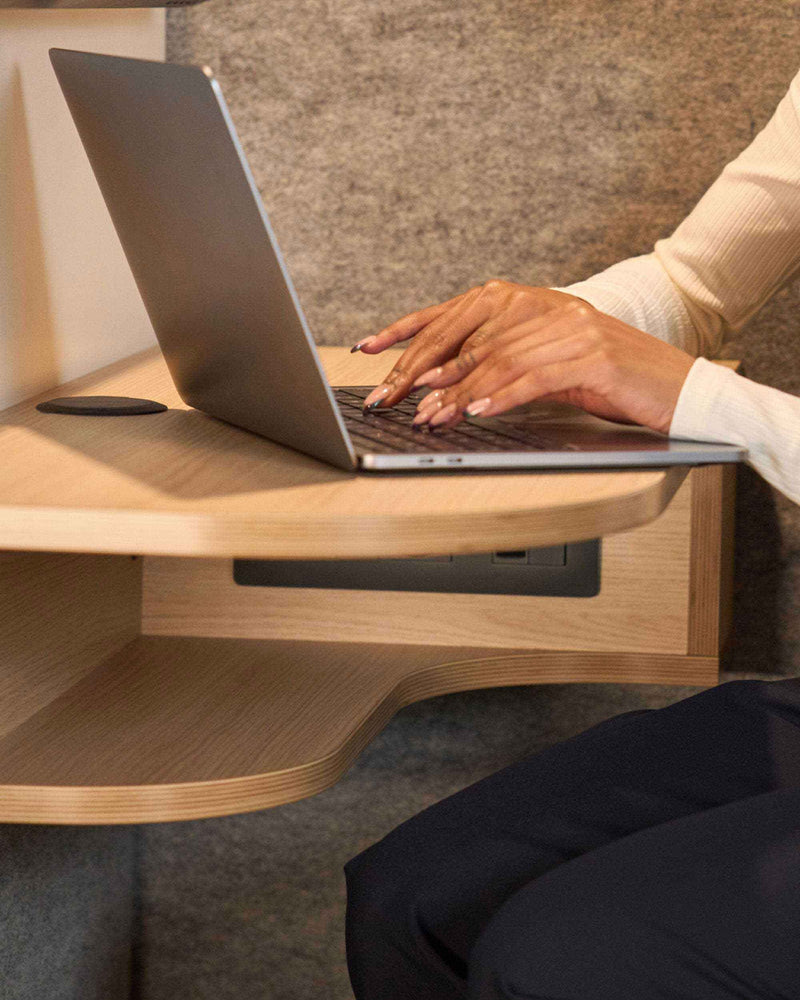 main qui tapent sun un ordinateur posé sur une tablette en bois