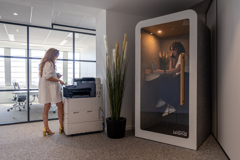femme devant une imprimante et femme au téléphone dans une cabine individuelle