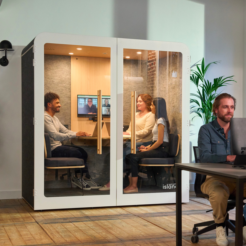 cabine pour quatre personnes, avec trois personnes en réunion, et un homme assis à son bureau